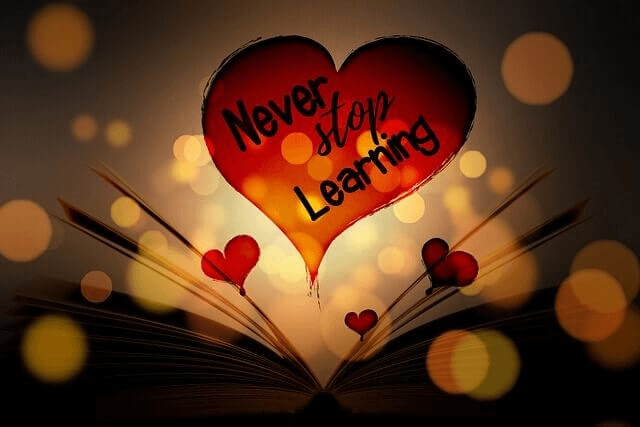 Rött hjärta med texten 'Never stop Learning' över en uppslagen bok, omgiven av tre små hjärtan och belyst bakifrån av orangea och gula ljuspunkter. Bilden har en mörkbrun bakgrund och används till ett inlägg som uppmuntrar till att starta en studiecirkel med fokus på lärande och gemenskap.