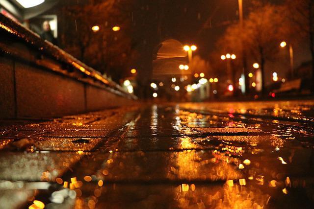 Lampor som reflekteras på en regnvåt gata. Bilden har varma färger och bidrar till namnsdags-inläggets visuella design.