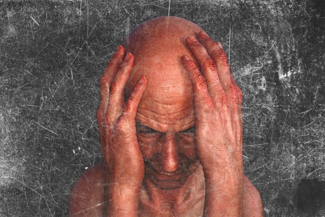 Medelålders man med huvudet i händerna, sittande mot en sliten grå bakgrund. Bilden används för att illustrera ett inlägg om stöd och hjälp vid förvirring.